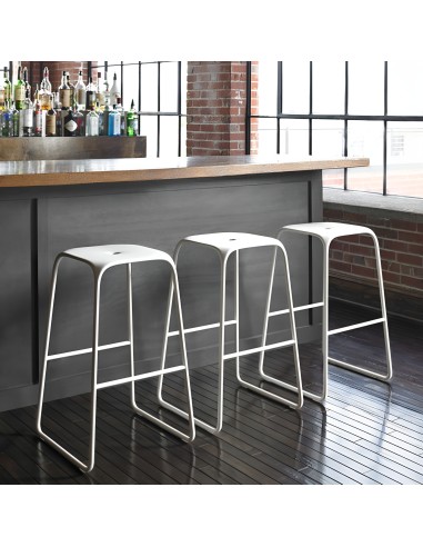 Tabourets Bobo blancs alignés devant un bar en bois dans un intérieur industriel – ambiance loft