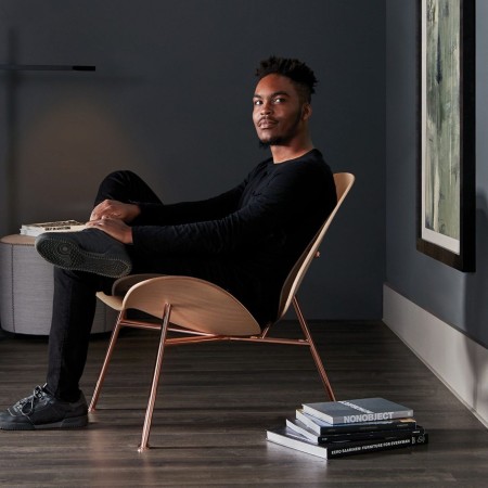 fauteuil design en bois clair et laiton antique dans un intérieur cosy et sombre