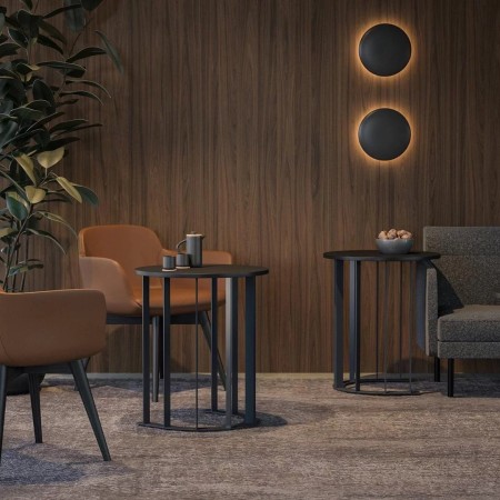 Tables basses rondes noires métal dans salon moderne avec fauteuils marron