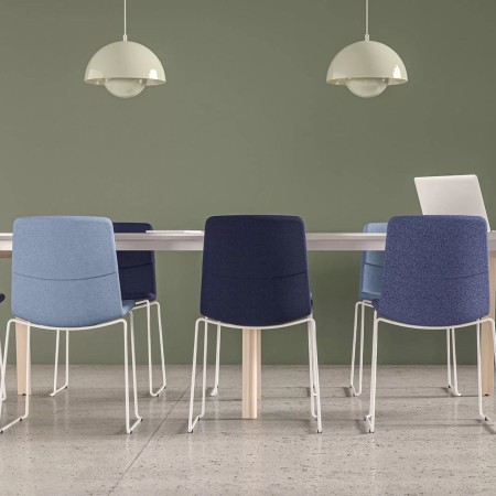 Table de réunion blanche avec piétement bois clair et chaises bleues claires et foncées