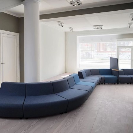 Système modulaire en forme de S avec canapés bleus, un écran et tablette intégrée