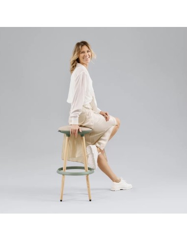 Femme assise sur un tabouret Cannie en pose dynamique sur fond gris – Cannie