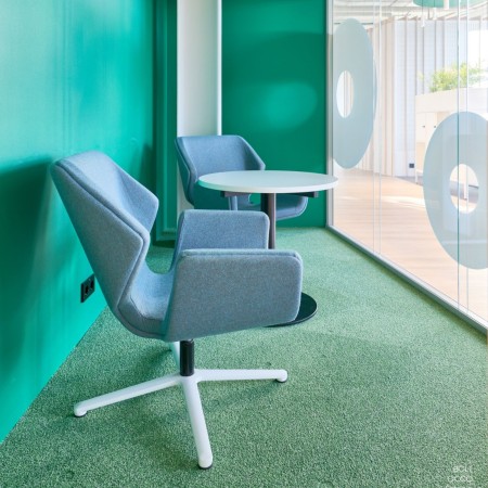 Fauteuil Booi Lounge en tissu bleu clair avec repose-pieds assorti dans un intérieur aux murs verts – Booi Lounge