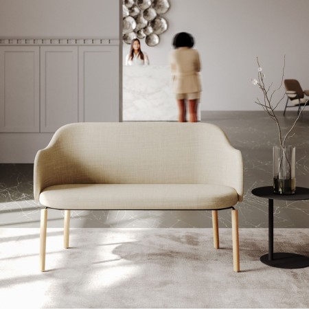 Femme assise sur un banc Flos beige dans un grand hall - Flos