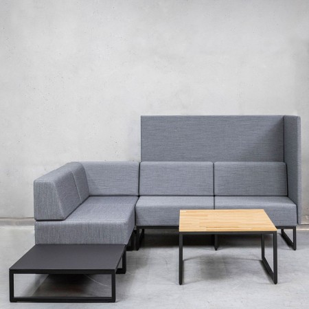Un ensemble modulaire gris clair comprenant des assises Plint associées à une table basse en bois clair, formant un coin détente