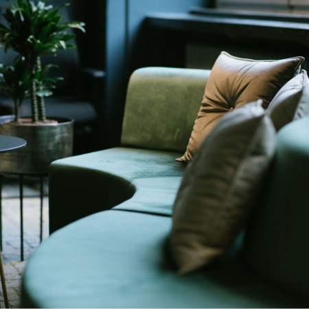 Gros plan d’une assise verte avec coussins dorés. - Quadra