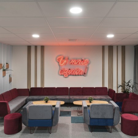 Espace détente avec canapés rouges et mur à néon lumineux. - U Floe