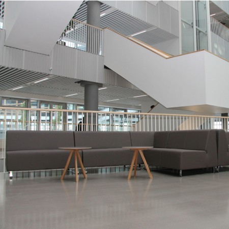 Hall spacieux avec banquettes grises et architecture ouverte. - Voo Voo