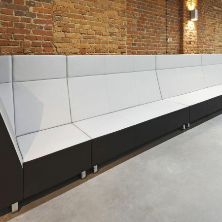 Banquette Voo Voo High installée le long d’un mur en briques dans un espace de détente. - Voo Voo High