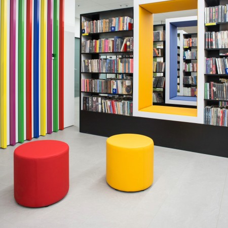 Poufs Rondo rouges et jaunes devant une bibliothèque colorée. - Rondo
