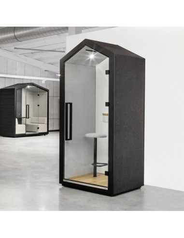 Utilisatrice debout dans la cabine Treehouse équipée d’un bureau haut. - Treehouse