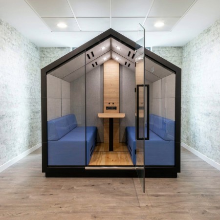 Cabine Treehouse vue intérieure avec deux assises en tissu bleu et table centrale. - Treehouse