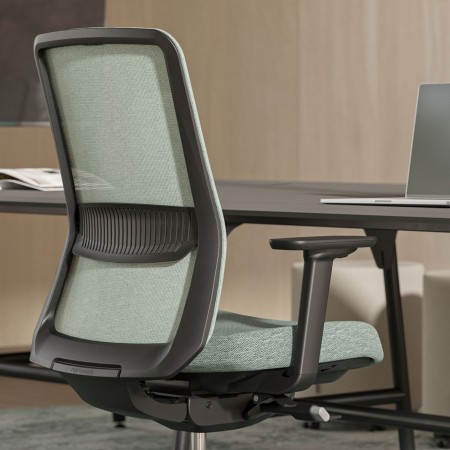 Chaise de bureau ergonomique EIRA avec dossier résille installé à un bureau à Lausanne.