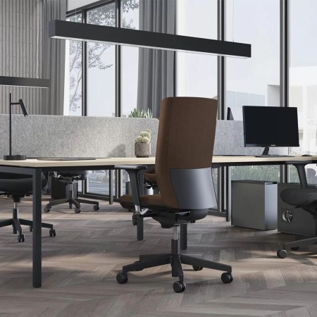 Chaise de bureau ergonomique brune AURA avec roulettes installée dans un open space à Sierre.
