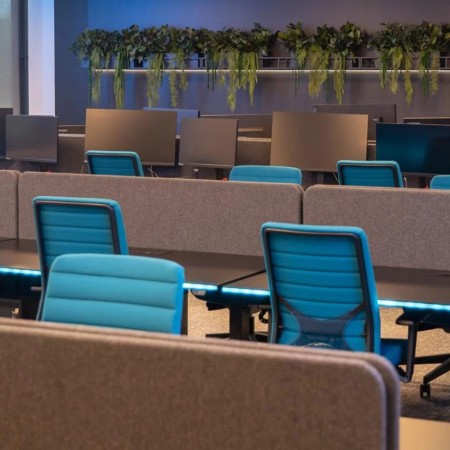 Chaises de bureau WIND en tissu bleu dans un espace collaboratif moderne avec bureaux bench et cloisons à Sion.