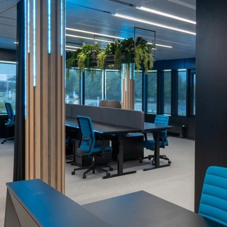 Chaise de bureau ergonomique WIND en tissu bleu installée dans un open space avec panneaux acoustiques à Viège.