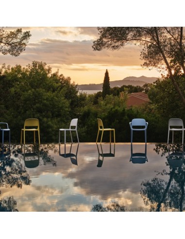 Chaises Blendy avec et sans accoudoirs en plusieurs coloris installées au bord d’une piscine extérieure.