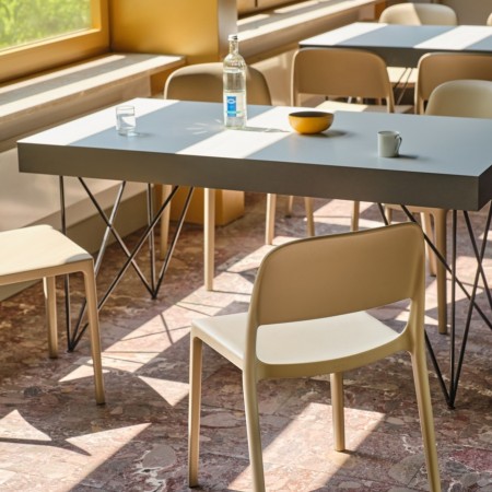 Chaises Blendy beige sans accoudoirs pour espace de restauration d’entreprise aménagé avec tables collectives.