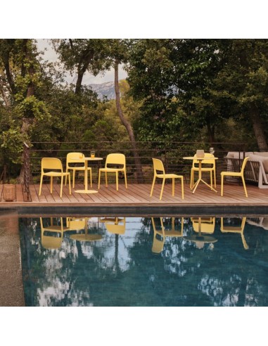 Chaises Blendy jaunes sans accoudoirs pour terrasse d’hôtel avec espace lounge et piscine extérieure.
