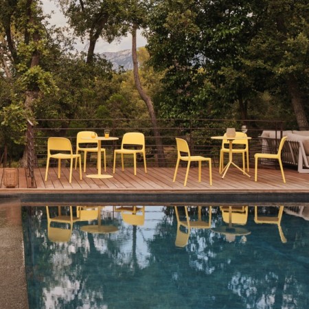 Chaises Blendy jaunes sans accoudoirs pour terrasse d’hôtel avec espace lounge et piscine extérieure.