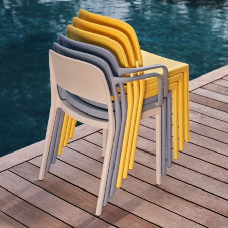 Six chaises Blendy empilables avec et sans accoudoirs en plusieurs coloris sur une terrasse extérieure.