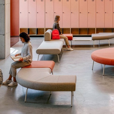 Banquettes modulables LINJE aux formes courbes aménagées dans un espace d’attente collectif avec casiers à Genève.