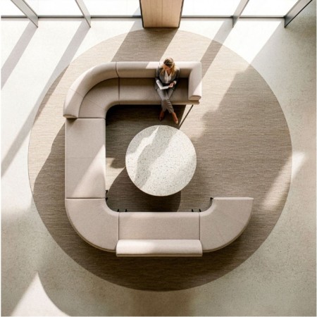 Vue de dessus d’un canapé modulable beige en configuration ouverte autour d’une table basse ronde.