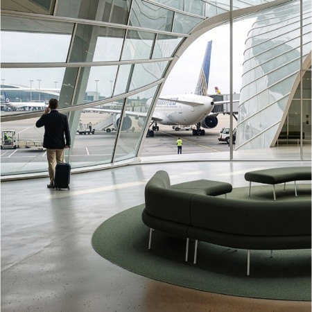 Banquette courbe modulable LINJE verte dans un espace d’attente d’aéroport à Genève.