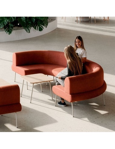 Canapé courbe modulable LINJE en tissu terracotta avec table basse dans un espace lounge professionnel à Lausanne.