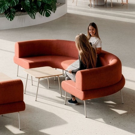 Canapé courbe modulable LINJE en tissu terracotta avec table basse dans un espace lounge professionnel à Lausanne.